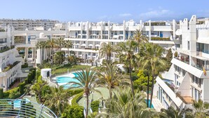 A modern hotel with multiple balconies, a swimming pool, and lush greenery. - Marbella Pool House PH78 On Sea Shore, Marbella, Spain (Marbella)