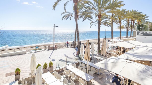 A seaside patio with tables and chairs, palm trees, and a view of the ocean. - Marbella Pool House PH78 On Sea Shore, Marbella, Spain (Marbella)
