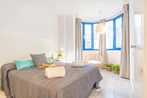 A modern bedroom with a large bed, a side table, a chair, and a window with curtains. - Marbella pool House GF55on sea shore, Marbella, Spain (Marbella)