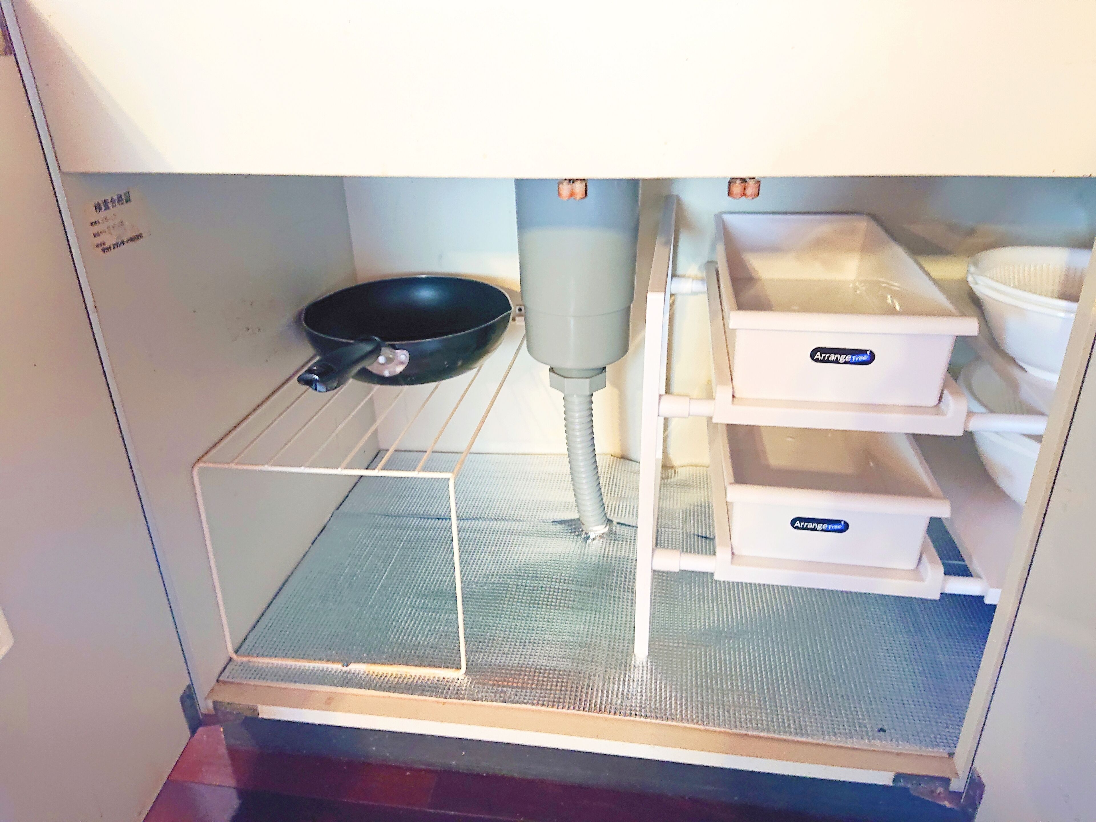 Cuina amb una paella negra, un rentapelats blanc i contenidors d'emmagatzematge blancs amb la inscripció "Arrange free".