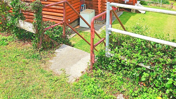Una cabaña de troncos de dos pisos con techo rojo, un pequeño porche y un letrero con el número 7.