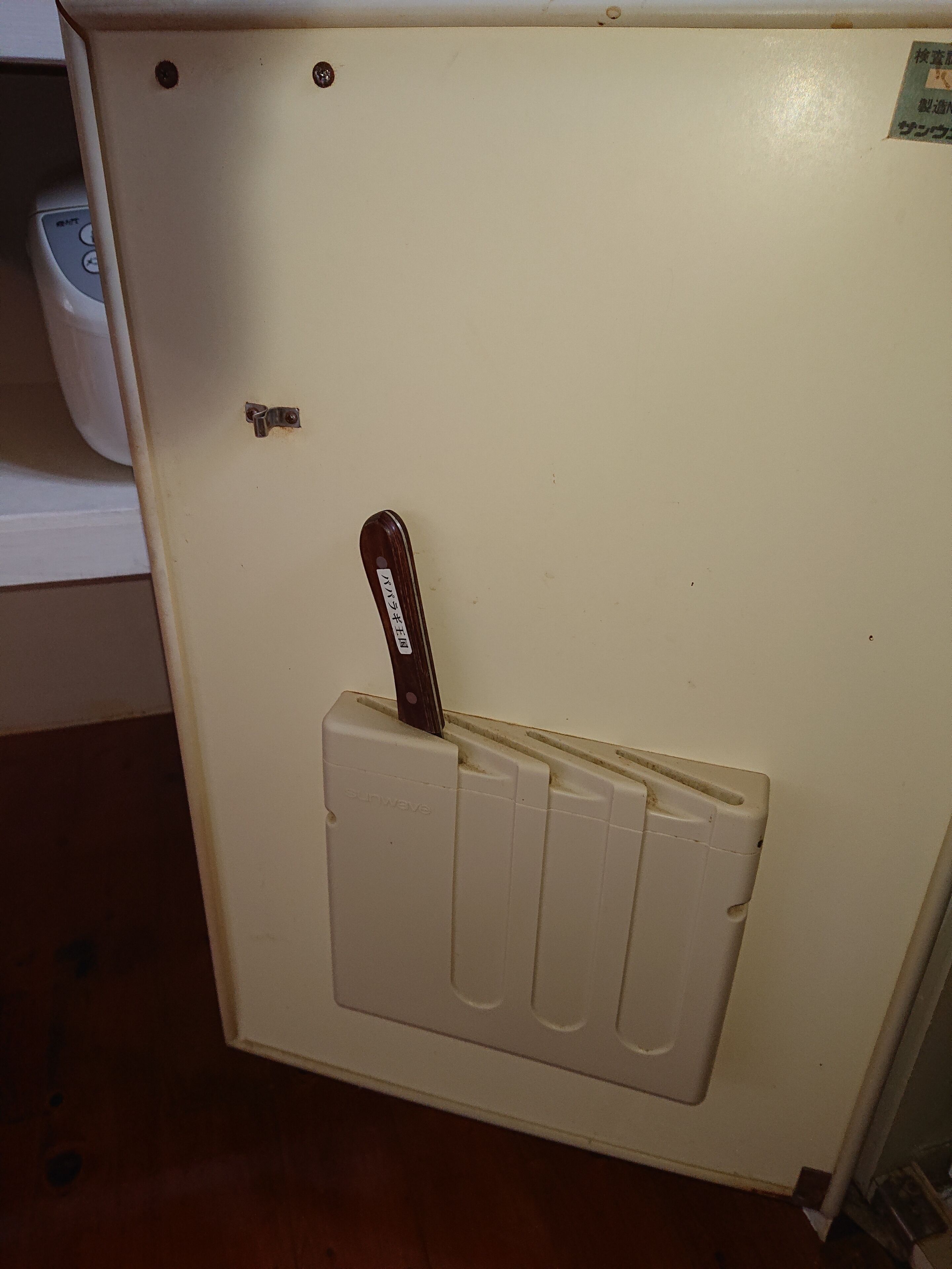 A white wall with a door handle and a small label.