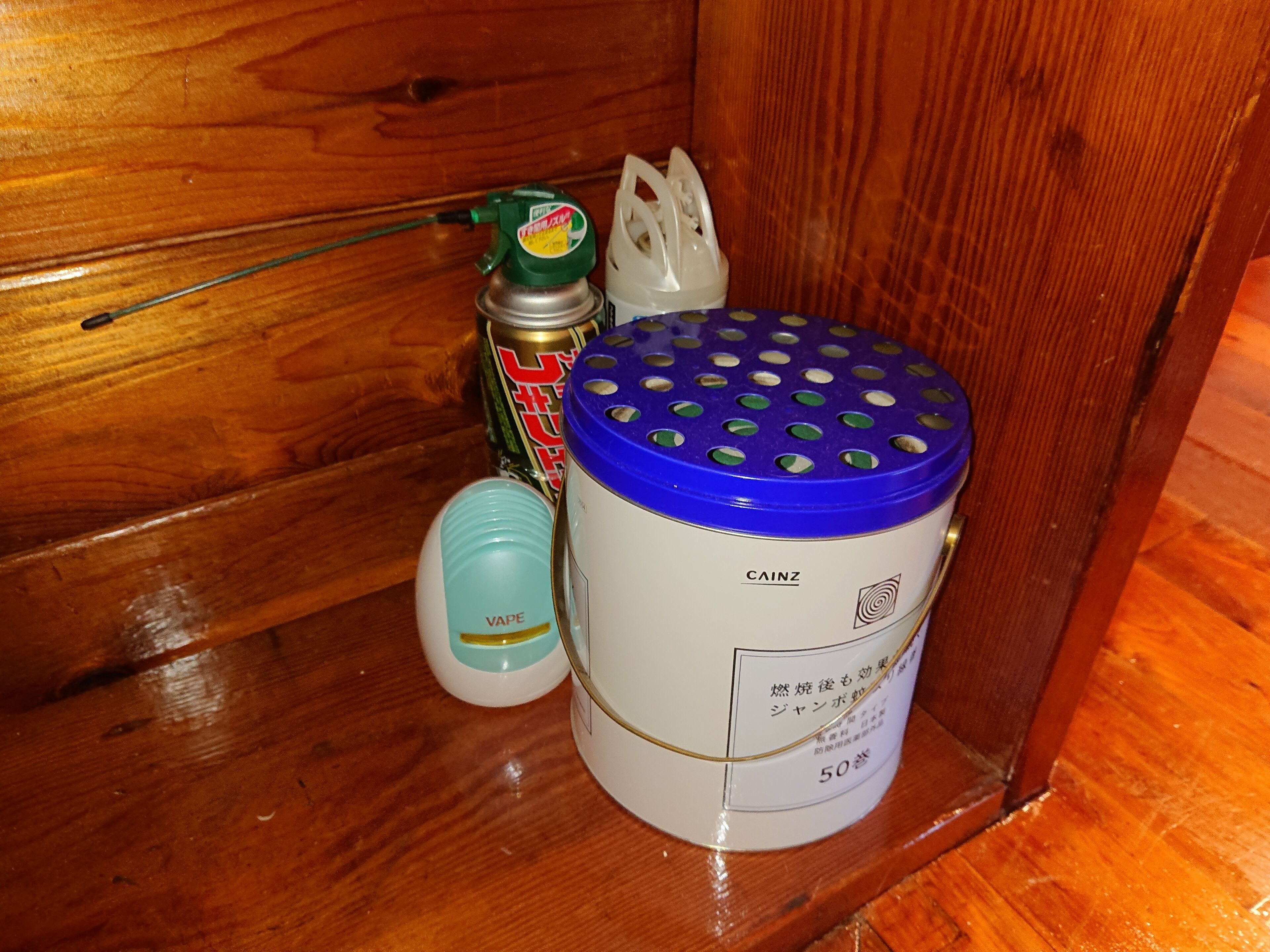 A wooden shelf with a vape device, a can, and a container labeled "CAINZ".
