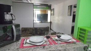 A kitchen with a dining table set for two, a microwave, and a green storage unit.