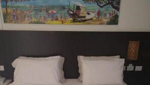A hotel room with a bed featuring a heart-shaped towel arrangement with pink flowers.