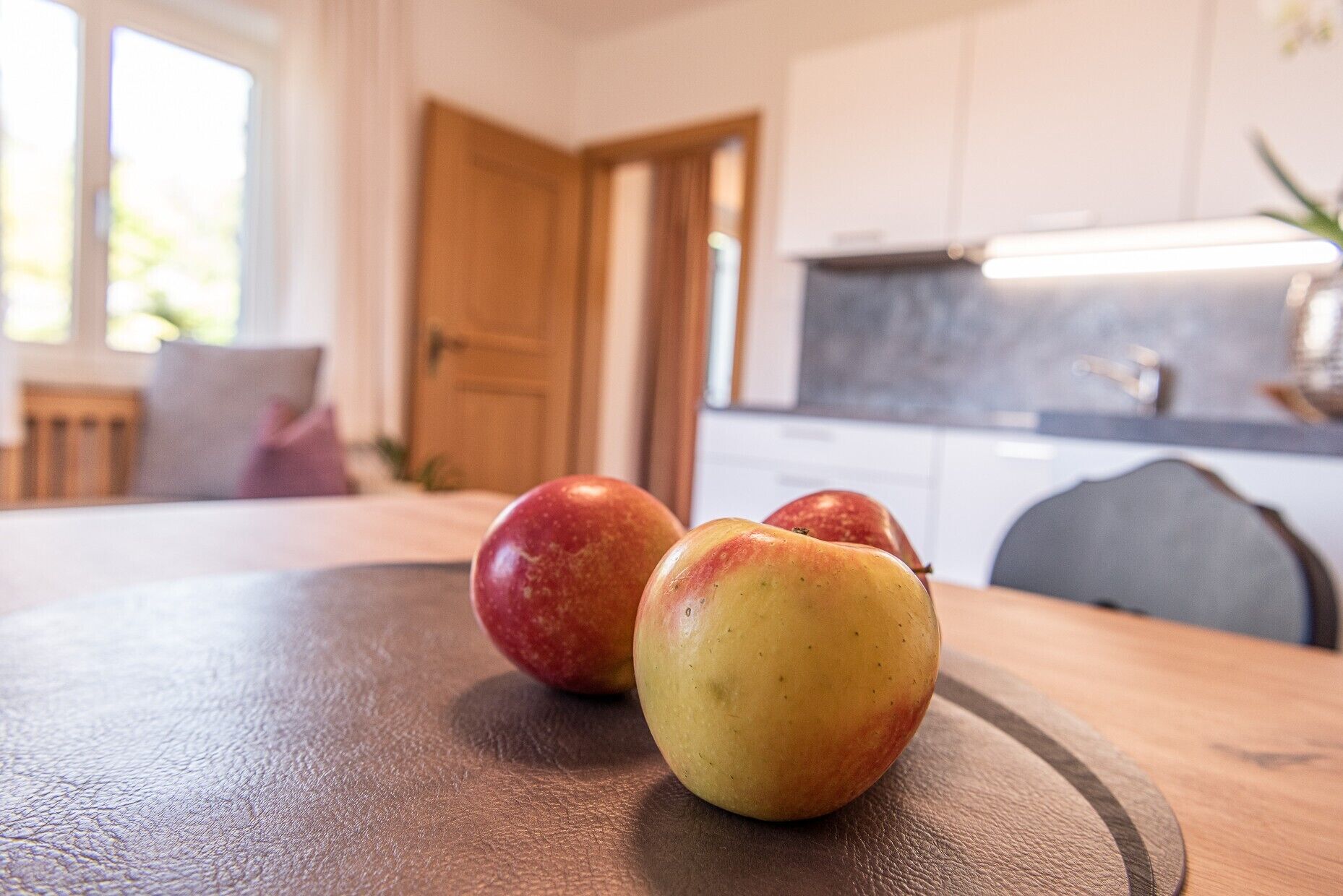 A wooden table with three apples.