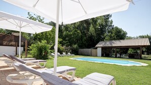 A backyard with a pool, lounge chairs, and a pergola.