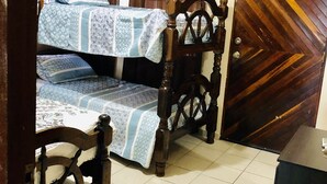 Ein Schlafzimmer mit einem Doppelbett, einem Holzkopfstück, Vorhängen und einem Fliesenboden.