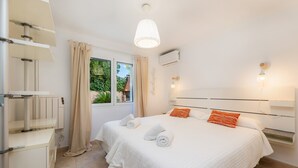 A hotel room with a bed, a window with curtains, a radiator, and a wall-mounted light fixture.