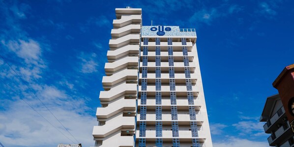 A tall hotel building with a prominent sign reading "ole" and balconies with blue railings. - oile by Zayra Resorts (Chatan)