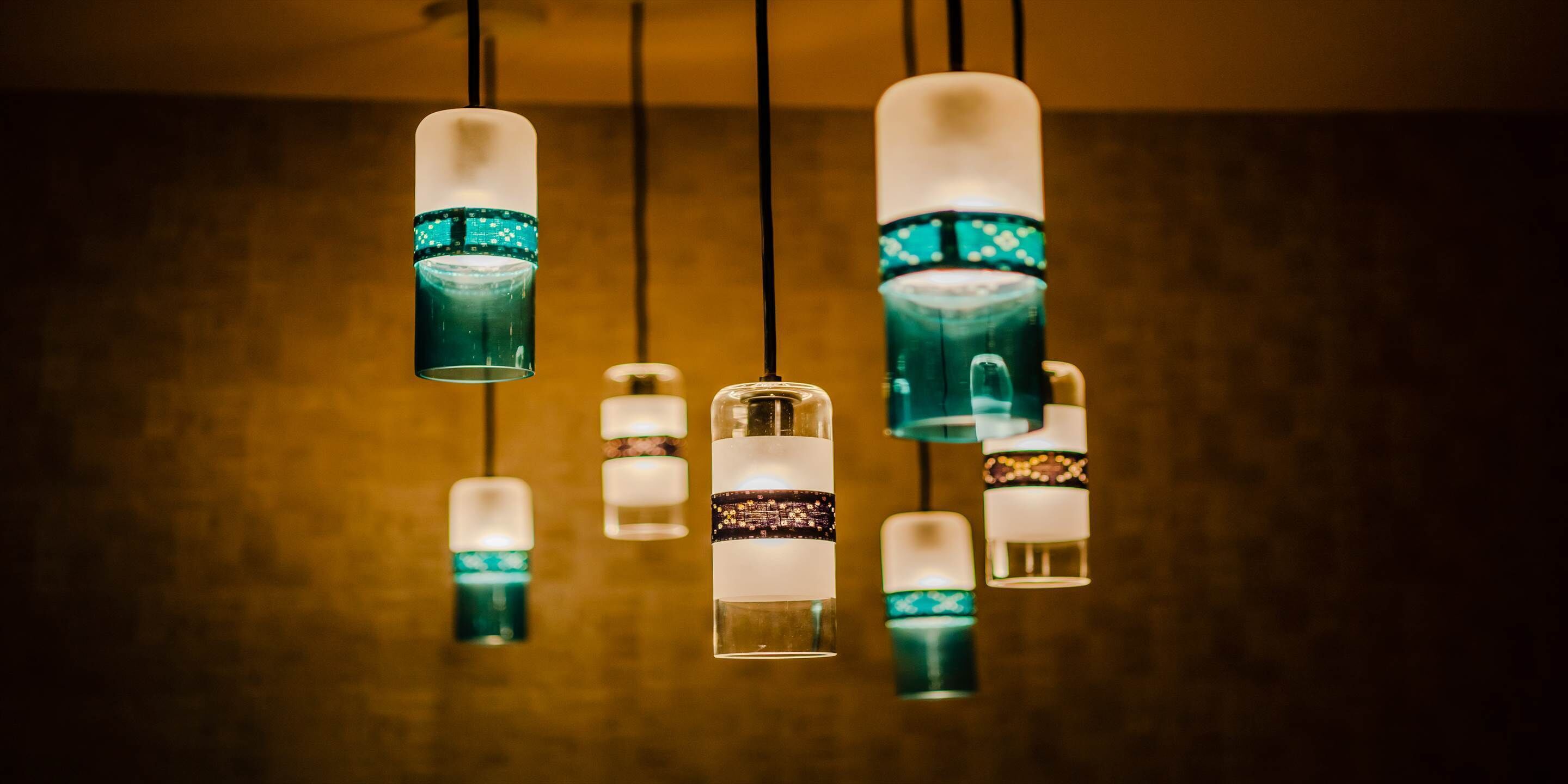 A series of pendant lights with a teal and white color scheme, hanging from a ceiling.