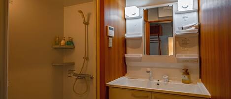 A bathroom with a shower, sink, and wooden cabinet.