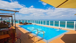 A pool area with a view of the ocean, deck chairs, and a bar area. - Oile by Zayra Resorts (Chatan)