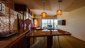 Une chambre d’hôtel moderne dotée d’un coin cuisine, d’une table à manger et d’une grande fenêtre donnant sur l’extérieur.