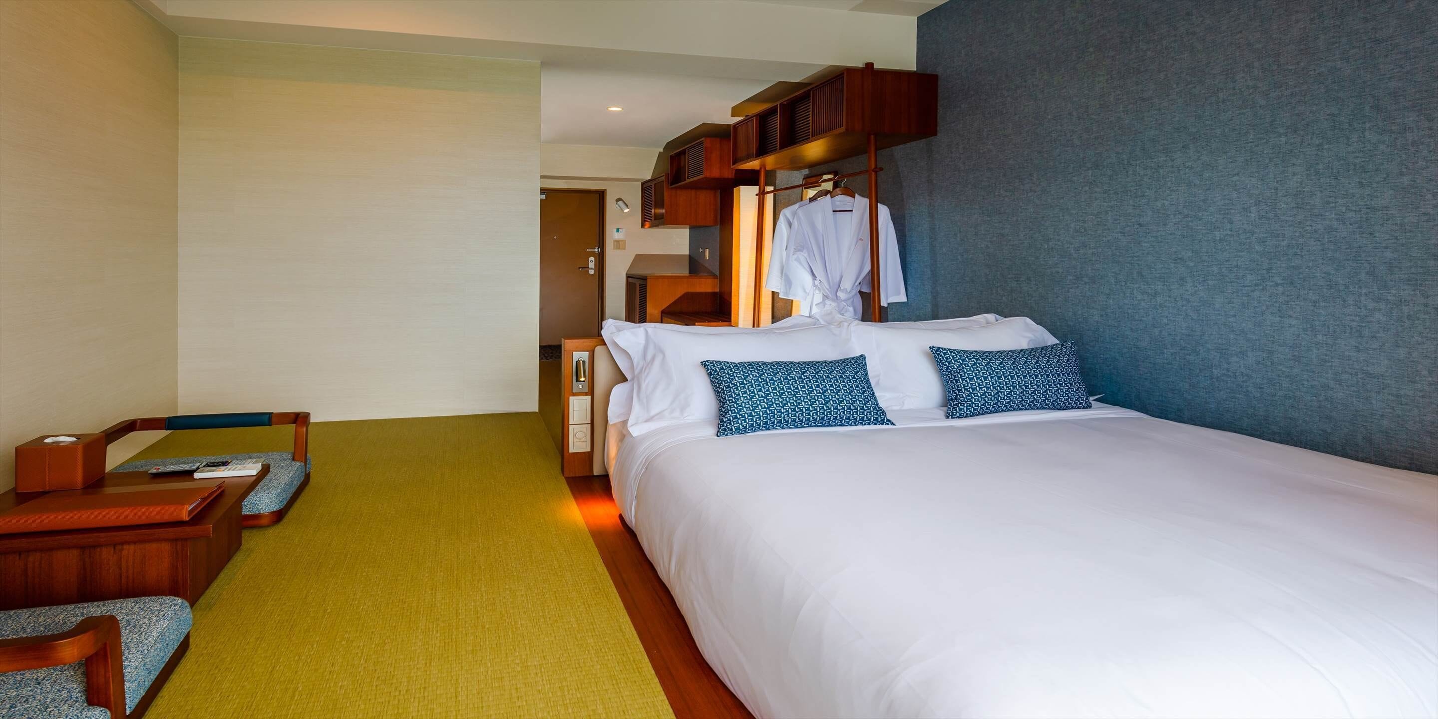 Una habitación de hotel con una cama grande, un escritorio de madera, una silla y una bata colgada en un perchero.