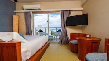 A hotel room with a bed, a TV, a small table with a clock, and a balcony with a view.