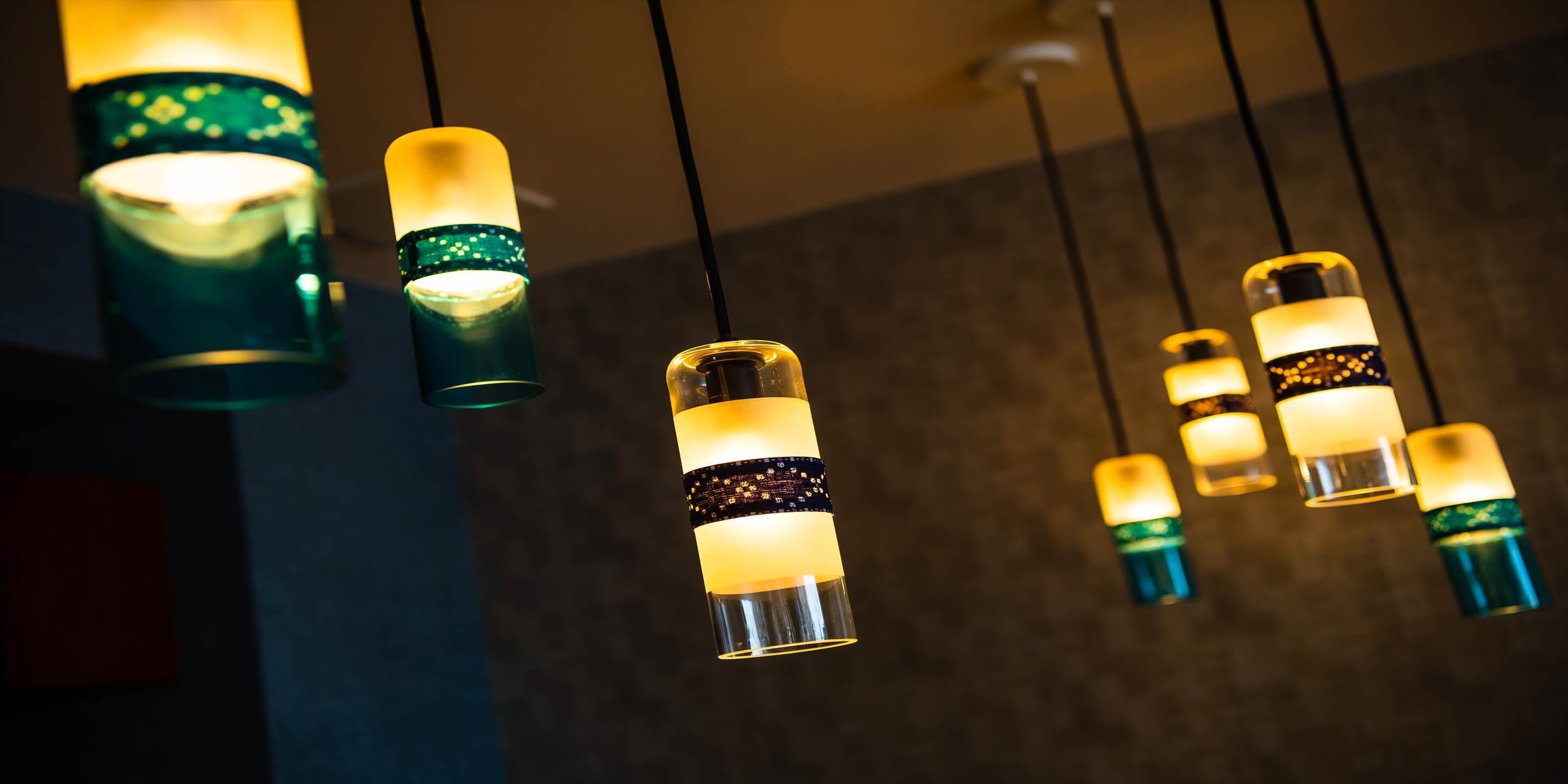 Una serie di lampade pendenti con luce calda, sospese al soffitto.