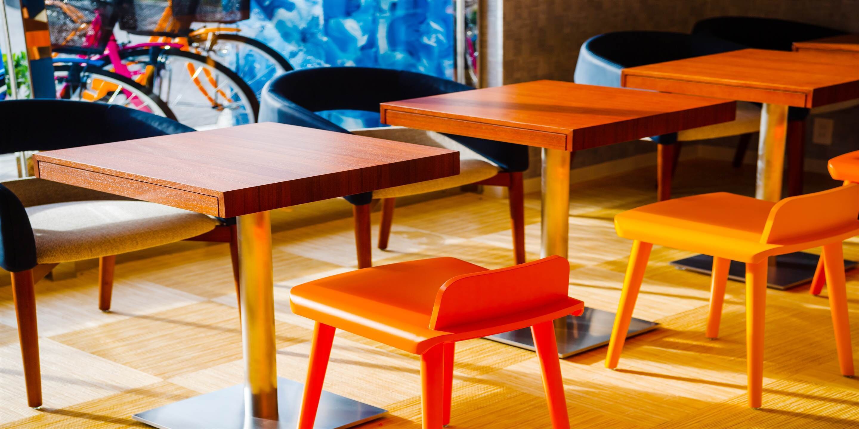 Een modern café met houten tafels en oranje stoelen.