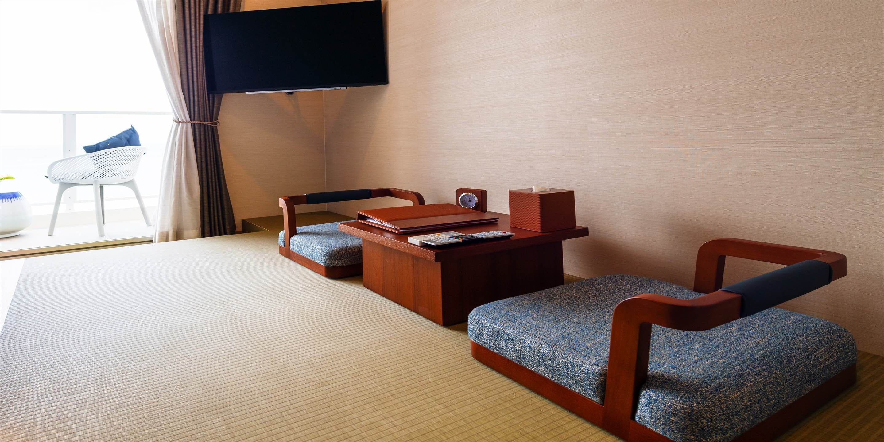 Una habitación con suelo de tatami, un escritorio de madera con televisor, una silla y una pequeña mesa.