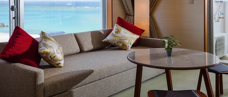 A modern hotel room with a sofa, a small table, and a view of the ocean.