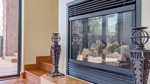 Ein moderner Kamin mit Glaseinsatz, begleitet von zwei verzierten Kerzenhaltern.