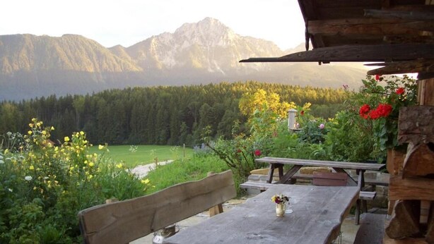 A rustic wooden table and bench set outdoors with a view of a mountainous landscape.