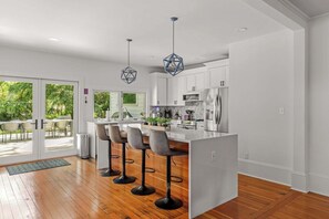 Une cuisine moderne avec un coin bar, un plancher en bois et une vue sur l’extérieur.