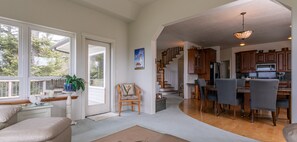 A spacious living area with a dining table and chairs, a kitchen with wooden cabinets, and a staircase leading to another level.