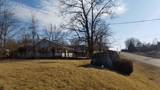 A rural landscape with a house, a large rock, and a grassy field. - Unity Lodge Suite 2 (Golconda)