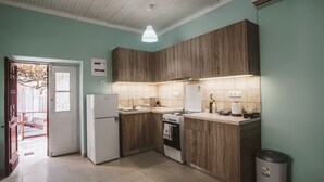 Een kleine keuken met houten kastjes, een witte koelkast, een fornuis en een spoelbak.