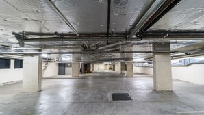 Un garaje amplio y vacío, con pilares de concreto, techo metálico con aislamiento térmico y un desagüe central.