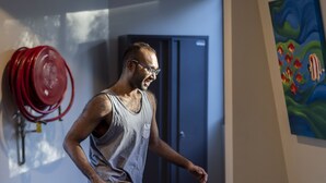 Una persona jugando al tenis de mesa en una habitación con una mesa de ping pong, una puerta y un cuadro en la pared.