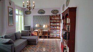 A cozy living room with a gray sofa, a wooden bookshelf, and a patterned rug. - Mas des Marbres Sauvages propriété 36 personnes (Sainte-Marie-la-Mer)