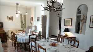 A dining area with a white tablecloth, wooden chairs, and a chandelier. - Mas des Marbres Sauvages propriété 36 personnes (Sainte-Marie-la-Mer)