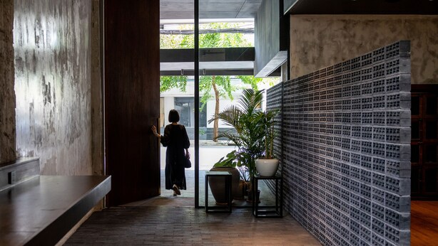 Un interior moderno con un banco de madera, una planta en maceta y una puerta de cristal que da al exterior.