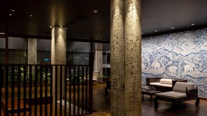 Un interior moderno con piso de madera, pared con diseño y una zona de estar con sofá y sillones.