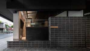 Una entrada moderna de edificio con estructura de hormigón, puerta de cristal y pared con diseño.