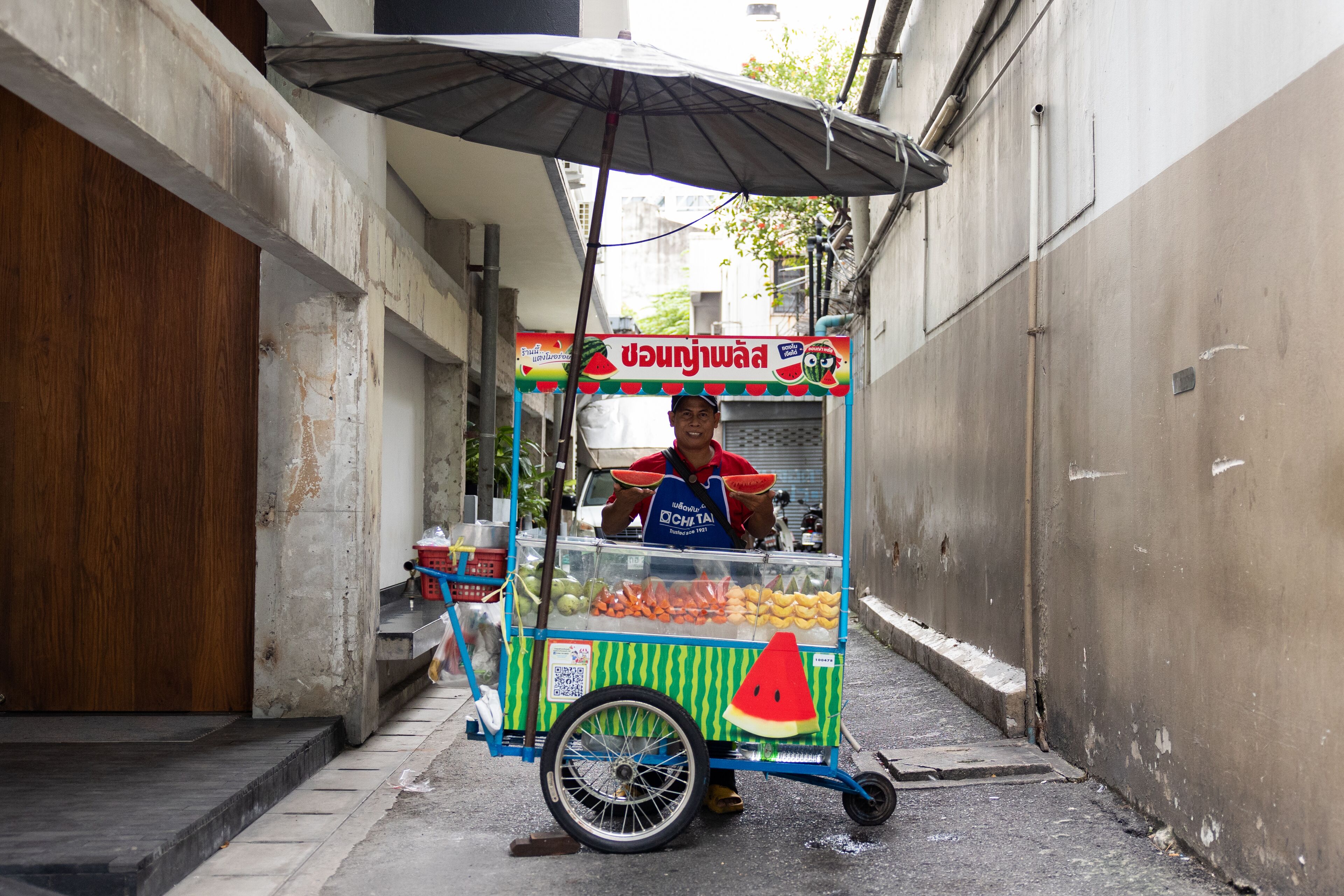 A street food cart with a watermelon graphic and a sign in a foreign language.
