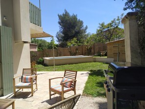 Un patio con dos sillas de madera y una parrilla.