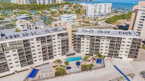 Un hotel moderno de gran altura con varios balcones, una zona de piscina y una playa.