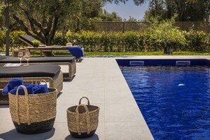 Ein Poolbereich mit Liegestühlen, einem Korbwicker-Korb und einer gefliesten Terrasse.