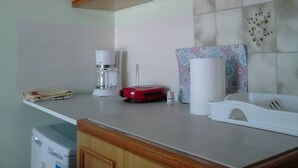 A kitchen with wooden cabinets, a coffee maker, a red appliance, and a patterned wall decoration. - Vasiliki's Apartment (Kalampaka center) (ΚΑΛΑΜΠΑΚΑ ΜΕΤΕΩΡΩΝ)