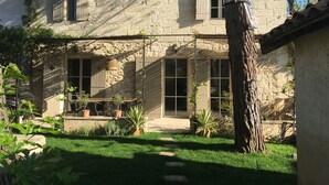 Ein rustikales Steinhaus mit Terrasse, Topfpflanzen und einem Baum.