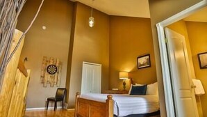A bedroom with a wooden bed, a chair, a desk, and a lamp. - 3-Story Condo / Mountain Views / Board Games (Fernie)