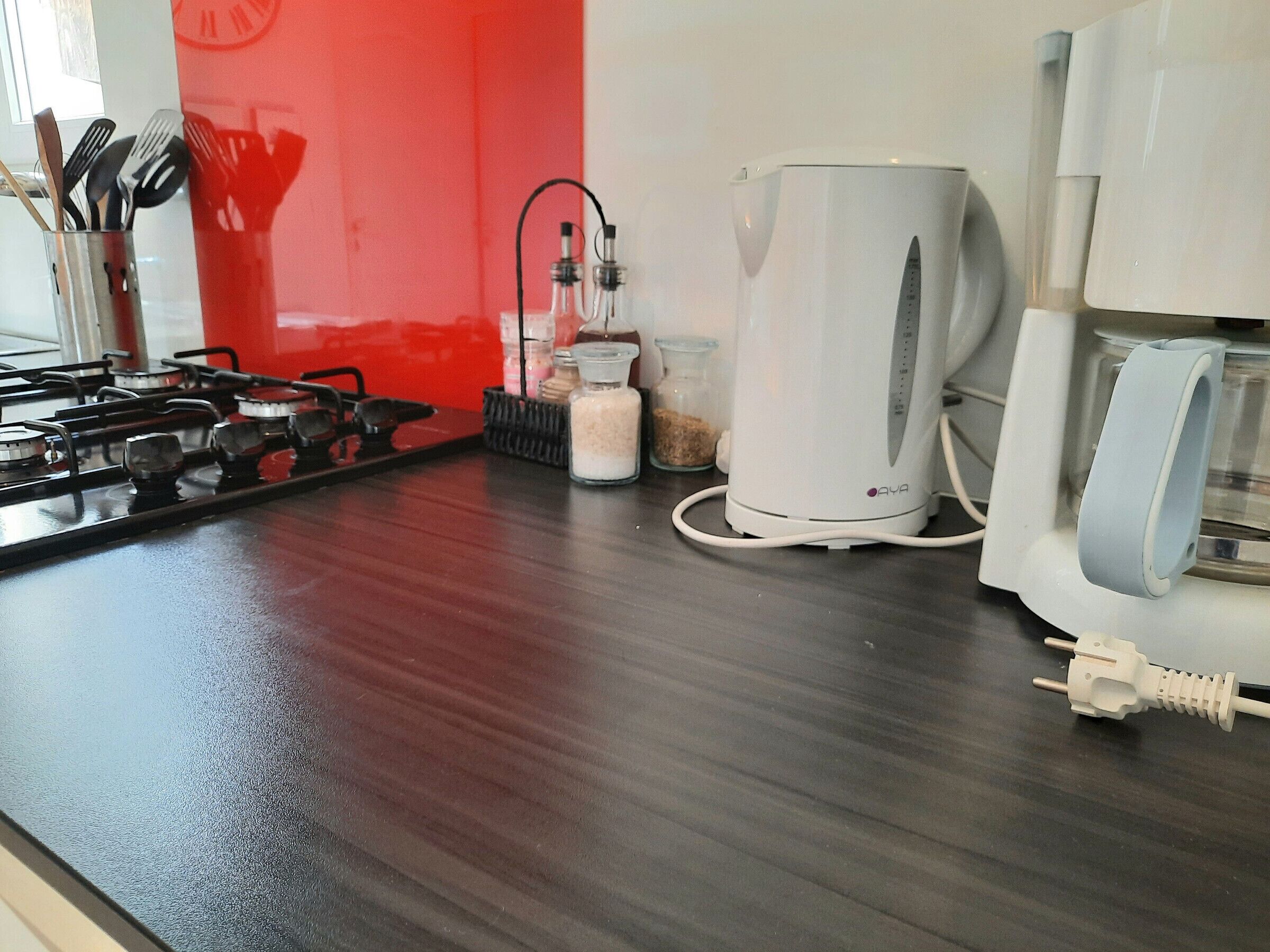 A kitchen with a gas stove, a coffee maker, and various kitchen utensils.