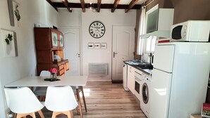 Ett kompakt kök med ett matbord, stolar, en klocka, en tvättmaskin och en mikrovågsugn.