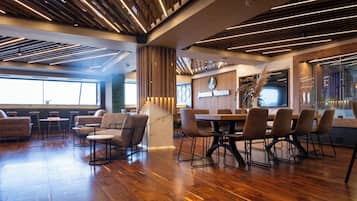 A modern restaurant interior with wooden flooring, high tables, and comfortable seating.