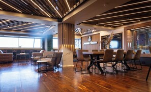 A modern restaurant interior with wooden flooring, high tables, and comfortable seating. - Villa San Giovanni Accommodation (Pretoria)