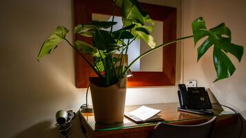 Een bureau met een bloempot, een telefoon en een lamp.