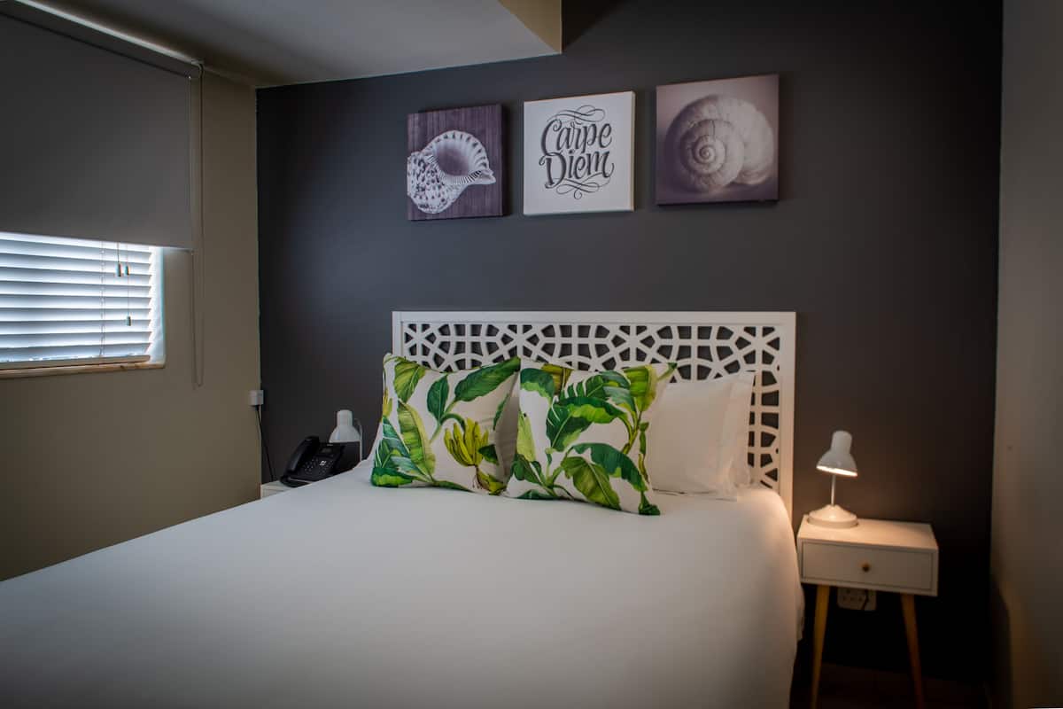 A bedroom with a bed, a nightstand, a lamp, and wall art.